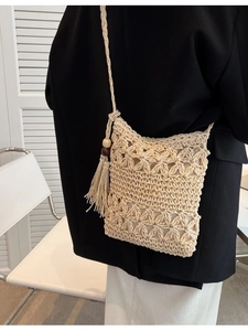 Hollow straw woven shoulder bag with floral pattern and tassel detail for summer vacations