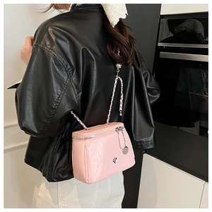 Detailed macro view of pink PU leather crossbody bag featuring silver floral buckle and chain