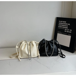 Chic woven bucket bags in black and cream featuring stylish chain straps and drawstring closures