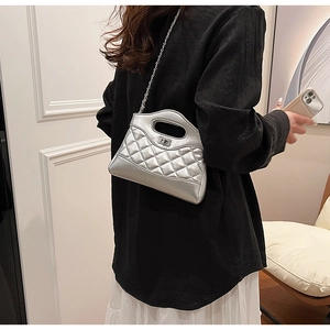Detail of silver quilted handbag featuring metallic chain strap and turn-lock closure