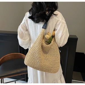 Detail of hand-woven straw tote with premium black leather straps and beige texture