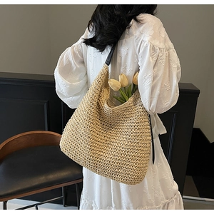 Detail of the large capacity straw tote bag featuring black leather shoulder straps
