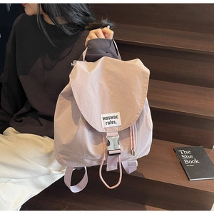 Close-up of light pink nylon drawstring backpack with metal buckle and branded woven label