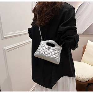Close-up of silver quilted chain bag featuring a sleek cutout handle and metallic finish