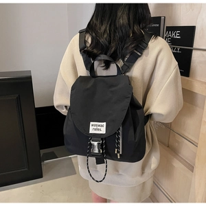 Detail of minimalist black nylon backpack with silver buckle and brand label on a model