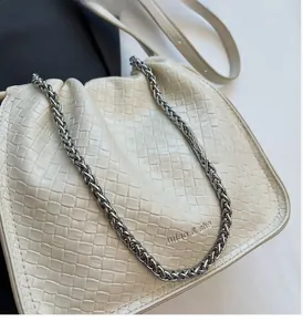 Close-up of beige woven bucket bag with silver metal chain and embossed logo