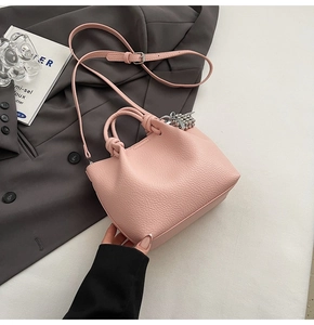 Detail of pink lychee leather bucket bag with knotted handle and strawberry charm