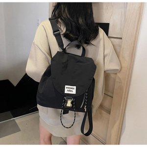 Detail of black nylon backpack featuring white fabric label and woven drawstring closure