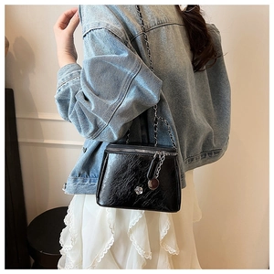 Detail of black pleated leather crossbody bag featuring a silver camellia metal buckle
