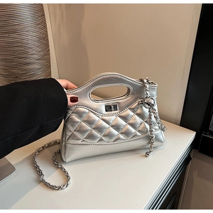 Macro detail of silver quilted metallic handbag featuring a twist lock and chain strap