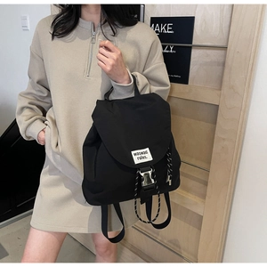 Detail of minimalist black nylon bucket backpack featuring silver buckle and drawstring cord