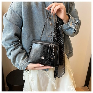 Detail showing the mini vanity bag with silver flower logo and woven chain strap