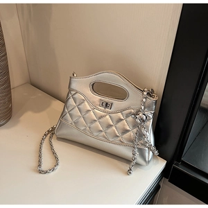Detail of silver quilted texture handbag featuring a metal turn-lock and chain strap