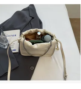 Macro view of interior storage of white woven bucket bag with chain strap and phone