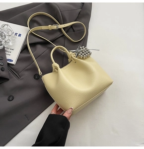 Detail of pale yellow bucket bag with lychee texture leather and silver bead charm