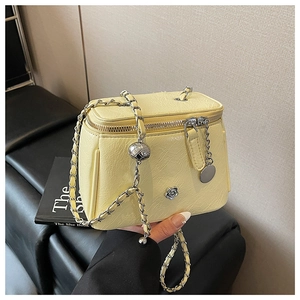 Détail du mini sac boîte jaune en cuir litchi avec breloque camélia et chaîne