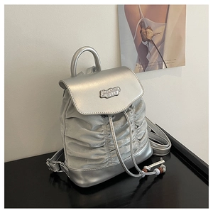 Details des silbernen Metallic-Faltenrucksacks mit Kordelzug und modischem Metallschild