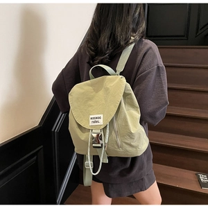 Rear view of a sage green nylon drawstring backpack with adjustable straps on a model