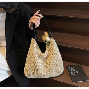 Detail of hand-woven straw hobo bag with black leather strap and large capacity