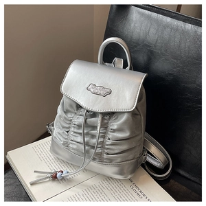 Detailansicht silberner Mini-Rucksack mit Kordelzug, Falten-Design und Logo-Plakette