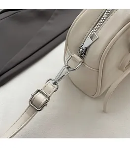 Dettaglio ravvicinato della ferramenta argentata e della pelle di una borsa a tracolla beige