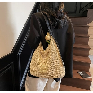 Detail of hollow straw tote bag with black adjustable leather strap and tulip decor