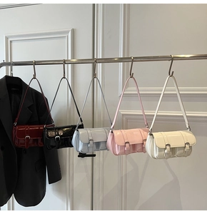 Collection of five glossy leather shoulder bags in various colors hanging on a rack