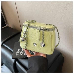 Détail du sac carré vert clair avec ornement camélia argenté et bandoulière