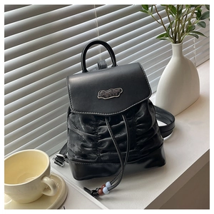 Detail eines schwarzen Mini-Rucksacks mit Faltsamt-Körper und Fashion BAG Metallplakette
