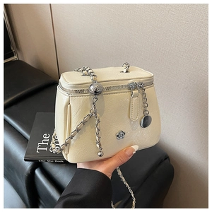 Détail du sac bandoulière crème avec chaîne argentée et boucle en métal fleurie