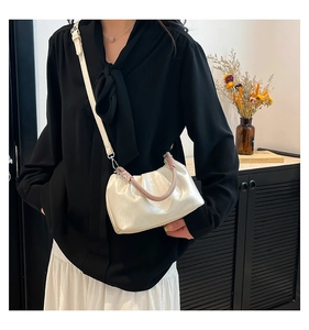 Detail of off-white pleated cloud bag showing woven handle and soft leather texture