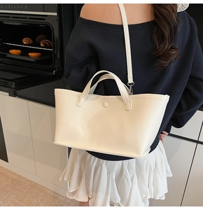 Model wearing a minimalist cream beige tote bag in a modern kitchen lifestyle setting
