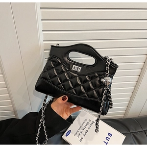 Detail of black quilted leather bucket bag with silver twist lock and chain strap