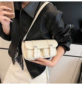 Detail of cream patent leather shoulder bag featuring vintage buckle pockets and retro design
