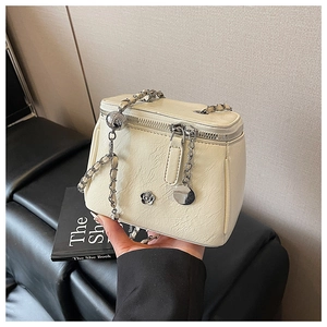 Détail du sac bandoulière blanc crème avec chaîne argentée et breloque fleurie