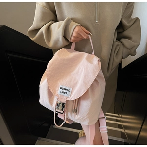 Detail of pink nylon bucket backpack showing drawstring closure and metal buckle