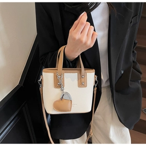 Detail of a chic bucket bag featuring lychee texture leather and a heart pendant charm