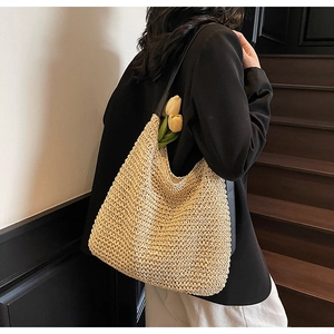 Detail of hand-woven straw hobo bag showing dense texture and sleek black shoulder strap