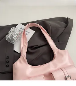 Pink PU leather tote bag with wide shoulder strap and side buckle pocket on a suit jacket