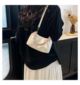 Model wearing a white ruched cloud bag with woven handle and slim shoulder strap