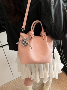 Pink lychee grain leather bucket bag with heart pendant and adjustable shoulder strap