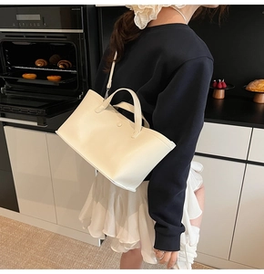 Detail of cream leather tote bag with shoulder strap shown in a modern lifestyle setting
