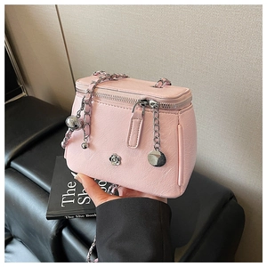 Détail du sac rose texture litchi avec fleur de camélia argentée et bandoulière