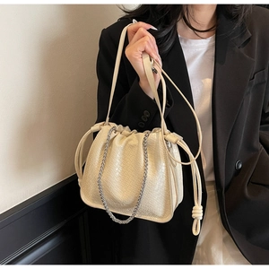 Close-up of woven texture detail on off-white bucket bag with silver chain strap