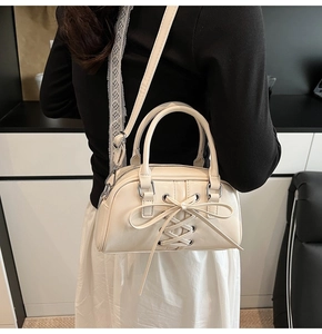 Dettaglio della borsa a bauletto crema con fiocco decorativo e nodi con coulisse
