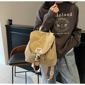 Detail of khaki canvas backpack with clip closure and brand tag in cafe setting