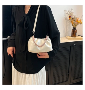 Detail of white pleated cloud bag with woven handle and adjustable strap on a model