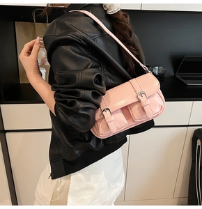 Close-up of pink patent leather shoulder bag featuring dual front pockets and silver buckles
