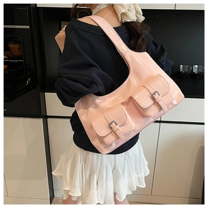 Detail view of pink patent leather hobo bag with dual front pockets and silver buckles