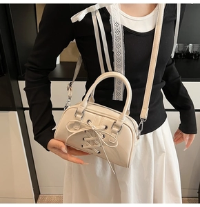 Dettaglio ravvicinato di una borsa in pelle verniciata bianco crema con fiocco decorativo
